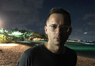 Aidan Gray, standing against the backdrop of a beach at night