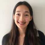 Head shot of a smiling Alice Huang, who has long, straight hair parted in the middle and is wearing a black shirt