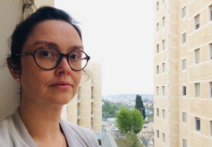 Alice stands on her balcony in Israel during a research stay