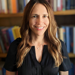 Woman with long hair in front of bookcases and wearing black shirt