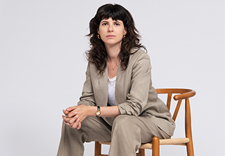Andrea Novakovic sitting on a chair in a suit looking at the camera