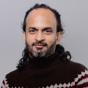 Man with hair pulled back, wearing a sweater