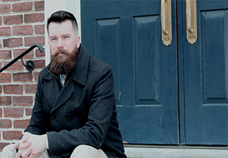 Daniel Scott Walsh sitting on steps in front of a blue door