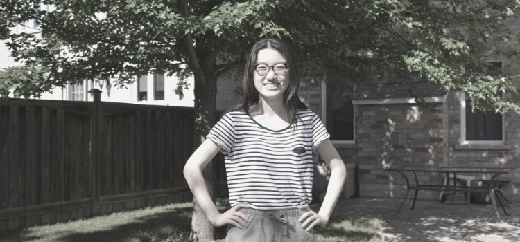 Elizabeth Zhu standing smiling in a sunny backyard, hands on her hips