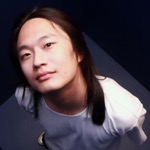 Head shot of Sanghun Han, an East Asian man with long black hair and wearing a white T-shirt, from above