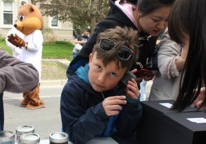 A kid puts a box up to his ear. 