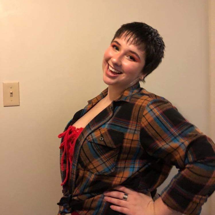 Headshot of Jordan, she's smiling and is wearing a a plaid shirt.