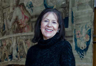 Head shot of a smiling Margie Morrison in front of a tapestry