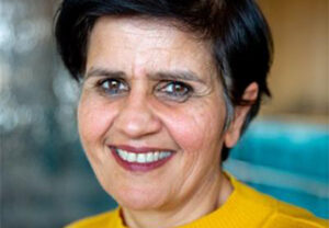 Close crop of a smiling Monima Chadha wearing a bright yellow top
