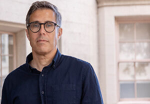 Head shot of Niko Kolodny, a middle-aged man with short salt-and-pepper hair, dark-rimmed glasses, and wearing a dark blue button-down shirt