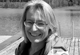 Black-and-white headshot of Ursula Renz in front of a mountain lake