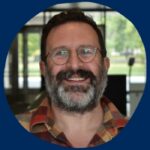 Head shot of a smiling Andrew Sepielli, gray beard and spectacles wearing a plaid shirt, on a U of T blue background and his name.