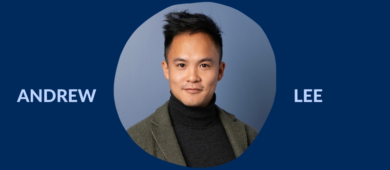 Headshot of Andrew Y. Lee, a young East Asian man wearing a blazer over top a black turtleneck and standing against a blue wall.