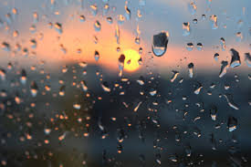 Raindrops on a window with sunset in back