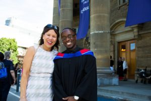 Female mentor and male graduate in convocation gown. 