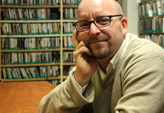 Headshot of Jeffrey Noonan, sitting in a library