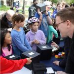L: the philsophy team poses at their science rendezvous booth; R: Michael Miller chats with kids.