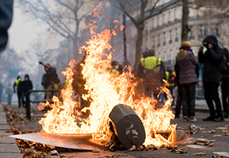 Yellow Vest protestors surrounding a protest fire in the smoky streets of Paris, France