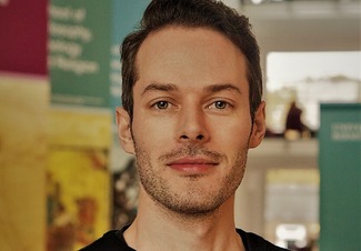 a headshot of Will Davies, a white man with short brown hair and stubble